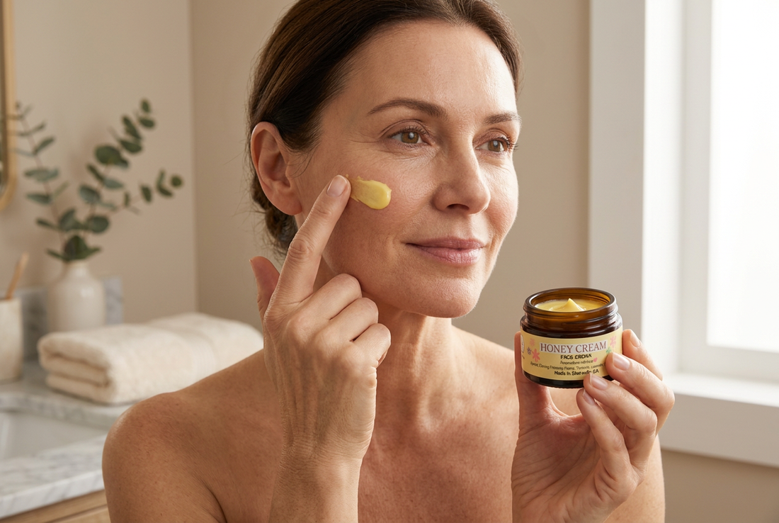 A woman gently applies yellow Honey Cream to her cheek while holding the jar, enjoying a nourishing moment of everyday skincare.